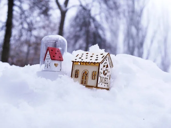 A pair of toy decorative houses with lighted illumination on the snow, the concept of winter seasonal holidays, Christmas, a new house in the new year, home comfort