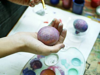  Bir fırça ile boya yumurta boyama Paskalya, arka plan sanat okulu Atölyesi, Paskalya tatili için hazırlık için öğrenci el tutar