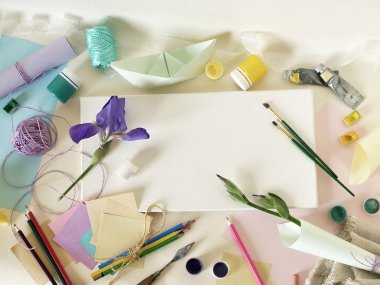 Masa üzerinde beyaz boş bir tuval, kopya alanı, çiçekler, sanat malzemeleri, üstten görünüm, kavramsal kompozisyon, yazma ve çizmek bir tebrik, davet, kartpostal