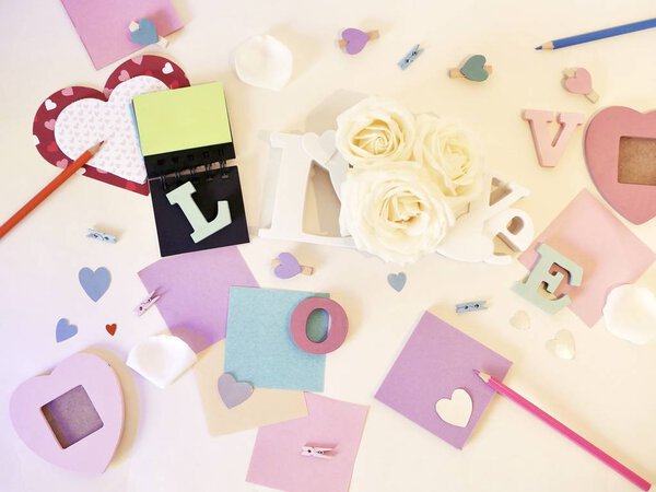 Декоративная композиция объемных букв, декора, роз, блокнота, карандашей на светлом фоне, концепция открыток, романтические поздравления
