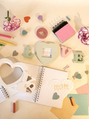 Taze pembe karanfil, ışıksız, Kalpler, boş dizüstü bilgisayarlar, boya kalemi, kağıt, kalem üzerinde hafif bir arka plan, üstten görünüm anneler günü kutlama için dekoratif kompozisyonu