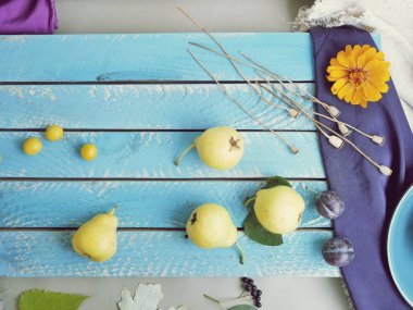 Sarı olgun armut ve Erik dağınık bir mavi ahşap masa, üstten görünüm, yaz, hasat, sağlıklı gıda kavramı