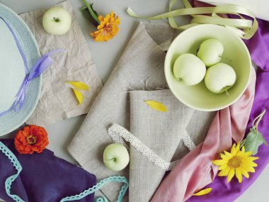 Elma, çiçekler, yaprakları, tuval, kağıt ve ipek kumaş, üstten görünüm, yaz, Sonbahar, seyahat için hazırlık kavramı sezon hafif bir arka plan üzerinde bir şapka dinlenme