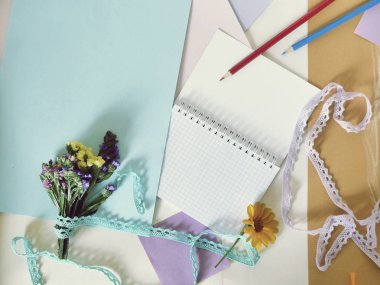 Kağıt, boş defter, küçük buket, masanın üzerinde kalemler, üst görünüm, çalışmanın başlangıcı veya sonu, tebrikler