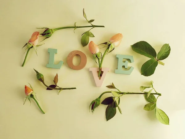 The word love is decorated with multicolored letters with rosebuds, petals and hearts, a romantic greeting