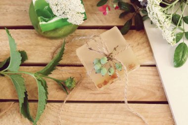 Ahşap bir masada doğal sabun, bitki ve çilek, spa prosedürleri, vücut bakımı, sağlıklı yaşam tarzı