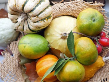 Bir saman sepeti parlak olgun mandalina ve balkabakları, sonbahar hasat kavramı, sağlıklı beslenme