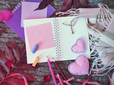 Bir çift keçe kalpler, bir eşarp, boş bir defter ve bir örme arka plan üzerinde kalemler, üst görünüm, romantik bir tebrik kavramı, sıcak sonbahar