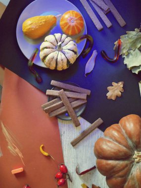 Balkabakları, yaprakları, çikolata kurabiyeleri, parlak bir arka planda jöle solucanlar, mavi ışık ile aydınlatılmış, masada, Cadılar Bayramı, Ekim dekoratif kompozisyon