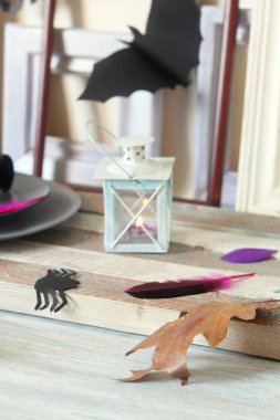 Mistik dekor, dekoratif bir fener yanan bir mum, çerçeveler, ahşap bir masa üzerinde sonbahar yaprakları, Cadılar Bayramı için iç hazırlık, Ekim