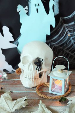 Kafatası, mistik dekor, aydınlatma, dekoratif fener, ahşap bir masada sonbahar yaprakları, Cadılar Bayramı için iç, Ekim