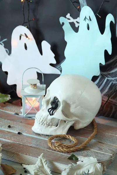 Kafatası, mistik dekor, aydınlatma, dekoratif fener, ahşap bir masada sonbahar yaprakları, Cadılar Bayramı için iç, Ekim