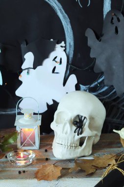 Kafatası, mistik dekor, aydınlatma, dekoratif fener, ahşap bir masada sonbahar yaprakları, Cadılar Bayramı için iç, Ekim