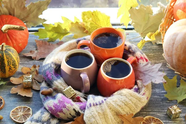 Üç fincan kahve, balkabağı, yapraklar, arka planda yün bir eşarp, ev konforu, aile, Şükran Günü, sonbahar sezonu