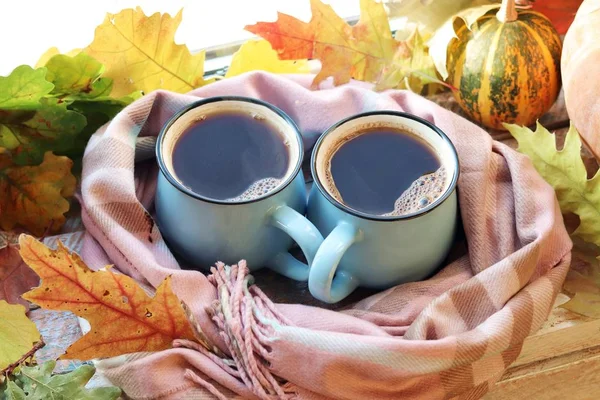 Two cups of coffee, pumpkins, leaves, a plaid on a window background, home comfort concept, Thanksgiving, autumn season