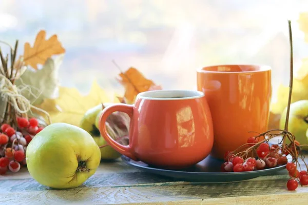İki fincan çay, meyve, böğürtlen, pencere arkasındaki ahşap masa yaprakları, romantik sonbahar kompozisyonu, ev konforu, sağlıklı yiyecek.
