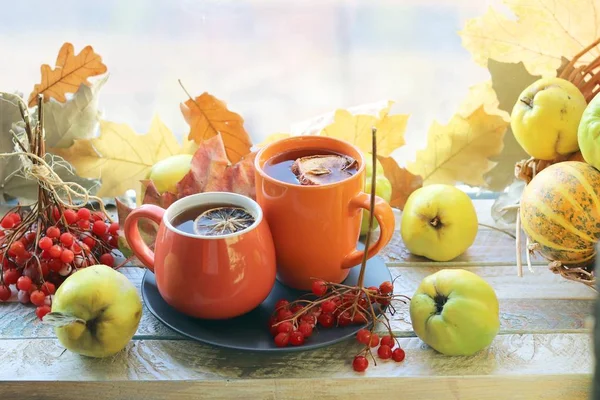 İki fincan çay, meyve, böğürtlen, pencere arkasındaki ahşap masa yaprakları, romantik sonbahar kompozisyonu, ev konforu, sağlıklı yiyecek.