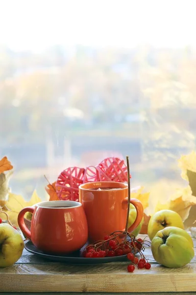 İki fincan çay, meyve, böğürtlen, pencere arkasındaki ahşap masa yaprakları, romantik sonbahar kompozisyonu, ev konforu, sağlıklı yiyecek.