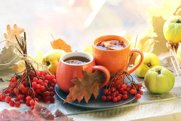 İki fincan çay, meyve, böğürtlen, pencere arkasındaki ahşap masa yaprakları, romantik sonbahar kompozisyonu, ev konforu, sağlıklı yiyecek.