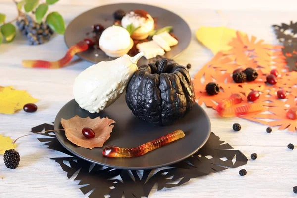 Halloween food, dessert with chocolate, pumpkins, ice cream and jelly worms on a wooden table