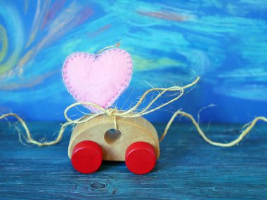 Oyuncak araba kompozisyonu ve mavi arka planda keçeden yapılmış bir kalp, Sevgililer Günü, tebrik kartı.