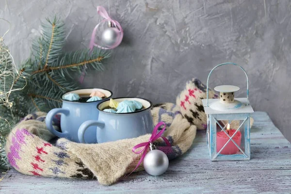 İki fincan kremalı kahve, Noel dekoru, yanan bir mum ile dekoratif fener pencere arkasında ahşap bir yüzey, aile kış tatili kavramı.