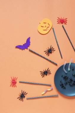 Cadılar Bayramı arkaplanı, böğürtlenli tabak, jöle solucanları, turuncu kağıttaki mistik dekor, tatil kartı konsepti, kopyalama alanı