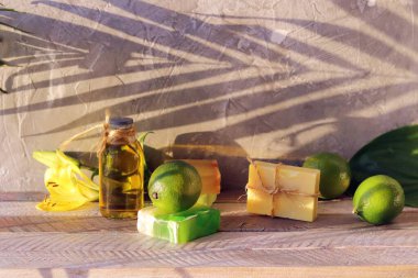 Sabun, limon ve şişe aromatik yağ, ahşap masa üzerindeki zambak çiçeği, vücut bakımı için doğal kozmetik ürünler.