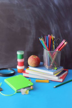 Okula dönüyorum, kırtasiye malzemeleri, büyüteç, kitap yığını, masada elma, evde öğrenim konsepti.