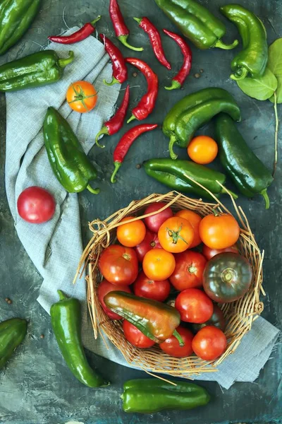 Masadaki domatesler, kırmızı ve yeşil biberler, bir sepet içinde, üst manzara, düz ley, hasat konsepti, sağlıklı mevsimlik yiyecekler, ev yemeği.