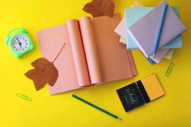 Okul kırtasiyesi, açık kitap, kalp şeklinde sayfalar, masada çalar saat, evde öğrenim konsepti, öğretmenler günü, okula dönüş. 