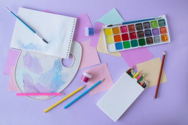 Okula geri dön, suluboya ve akrilik boya, fırça ve renkli kalemler, palet, çizim için okul gereçleri, mor arka plan