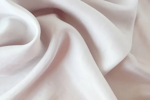 Katlarla örtülmüş bej rengi doğal ipek, üst görünüm, kumaş dokusu, pastel gölgeler arkaplan