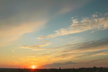 Bulutlar ve güneş ışınlarıyla şehirde güzel bir günbatımı. Güneş şehrin üzerinde batıyor..
