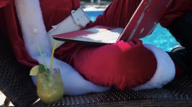 Dizüstü bilgisayar kullanarak ve yüzme havuzu yazarak Santa