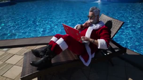 Santa drôle dactylographier à l'ordinateur portable pendant les vacances d'été — Video