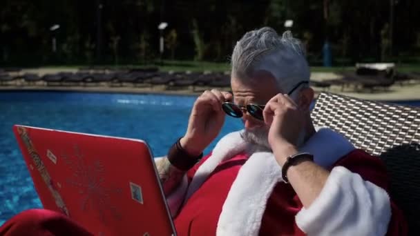 Santa koppla av vid poolen och göra galna skämt med laptop — Stockvideo