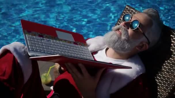 Santa sunbathing at swimming pool funny use laptop — Stock Video