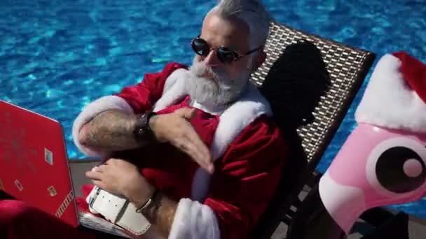 Funny Santa using laptop sit at chaise and joking — Stock Video