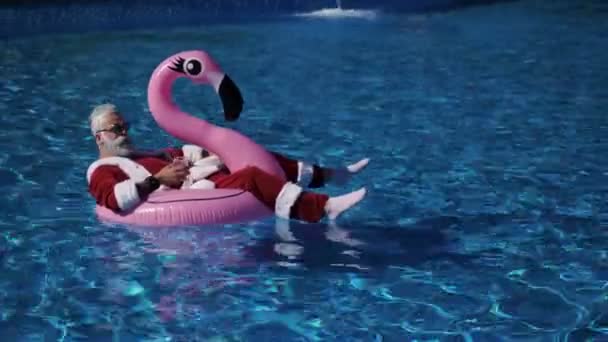 Санта плавает в неподвижном кольце в бассейне — стоковое видео
