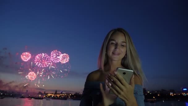 Femme avec téléphone à l'arrière-plan les feux d'artifice de la ville — Video