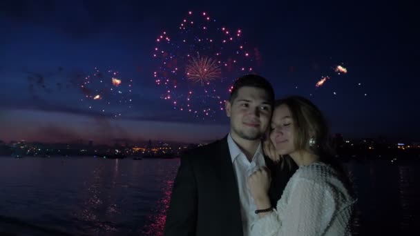 Fuegos artificiales y jóvenes amantes se abrazan en la noche — Vídeos de Stock