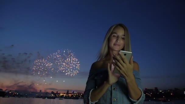 Femme avec téléphone à l'arrière-plan les feux d'artifice de la ville — Video