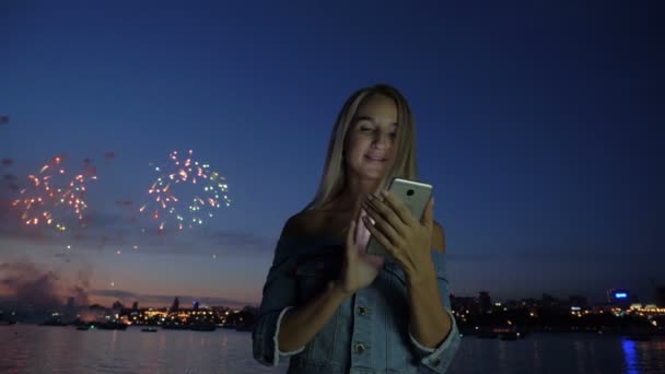 Жінка з телефоном на фоні міського феєрверку — стокове відео