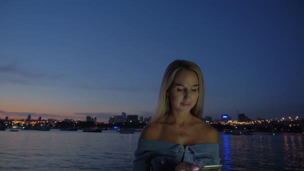 Όμορφη γυναίκα χρησιμοποιώντας το τηλέφωνο στο ηλιοβασίλεμα ανάχωμα — Αρχείο Βίντεο