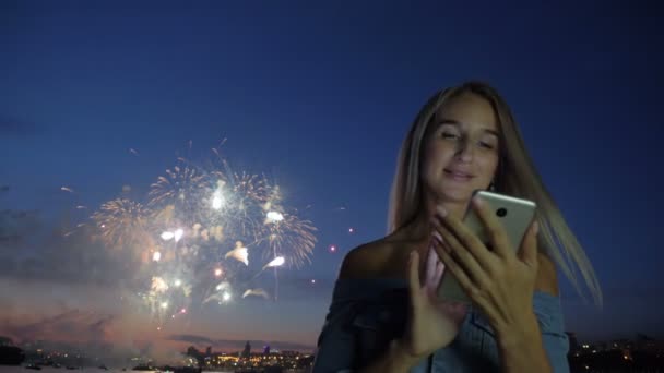 Жінка з телефоном на фоні міського феєрверку — стокове відео