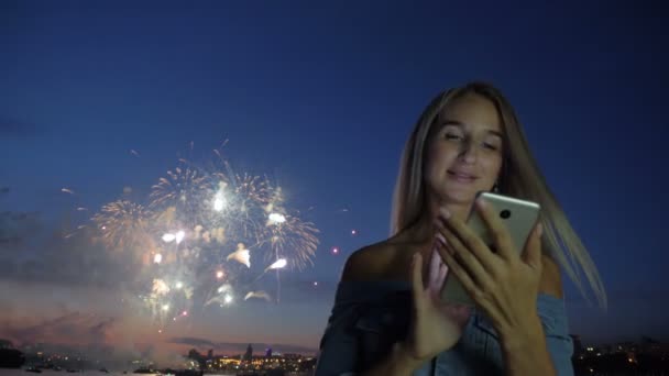 Femme avec téléphone à l'arrière-plan les feux d'artifice de la ville — Video