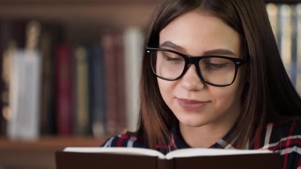 Chica sonriente disfrutar de la historia de caña en la librería de primer plano — Vídeos de Stock