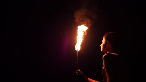 Hombre que respira fuego con antorcha en llamas en la noche — Vídeo de stock