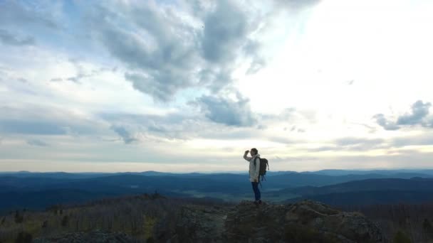 Turista stojí na vrchol hory a rozhlédl se kolem sebe — Stock video